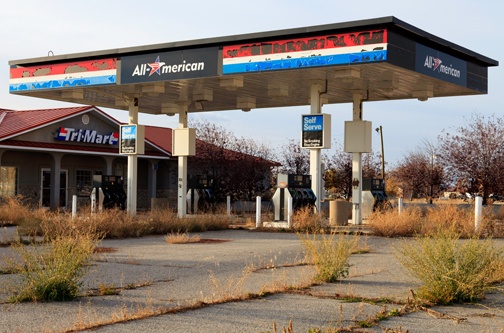 Old gas station with vegetation growing between cracks in the concrete